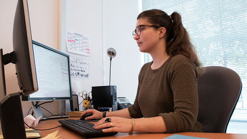 Jeune femme assise à son bureau travaillant sur un ordinateur