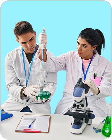 Un jeune homme et une jeune femme en blouse blanche assis à une paillasse manipulent un pipette, un Becher et un microscope.