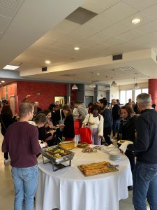 Beaucoup de monde dans une salle, autour d'un buffet de nourriture.